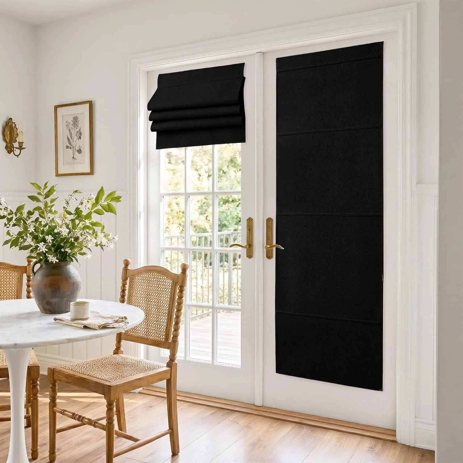 Black Roman shades on white French doors in a bright dining area with marble table and cane chairs.