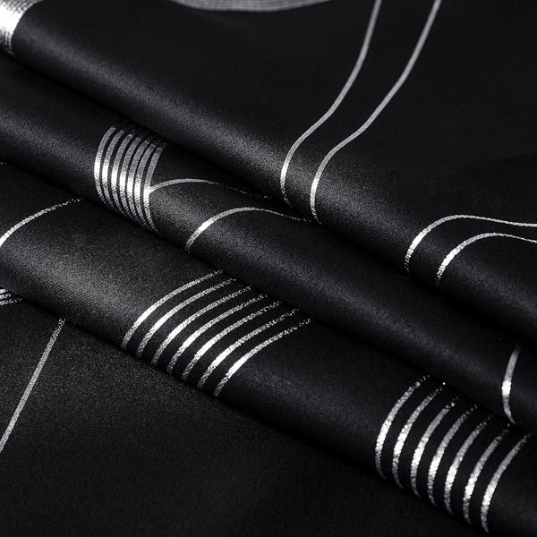 Close-up of elegant black drapery fabric with a shiny silver foil stripe and geometric pattern.