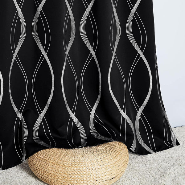 Black curtain with metallic silver wavy line pattern, draped over a natural woven stool.