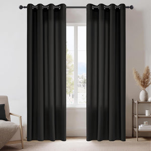 Pair of black solid blackout curtains with silver grommet tops hanging on a black rod in a living room.