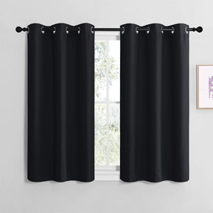 Pair of black solid smooth grommet top short curtains hanging on a dark rod over a window.