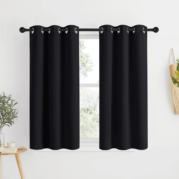 Two black solid grommet top curtains hanging on a black rod, covering a window.
