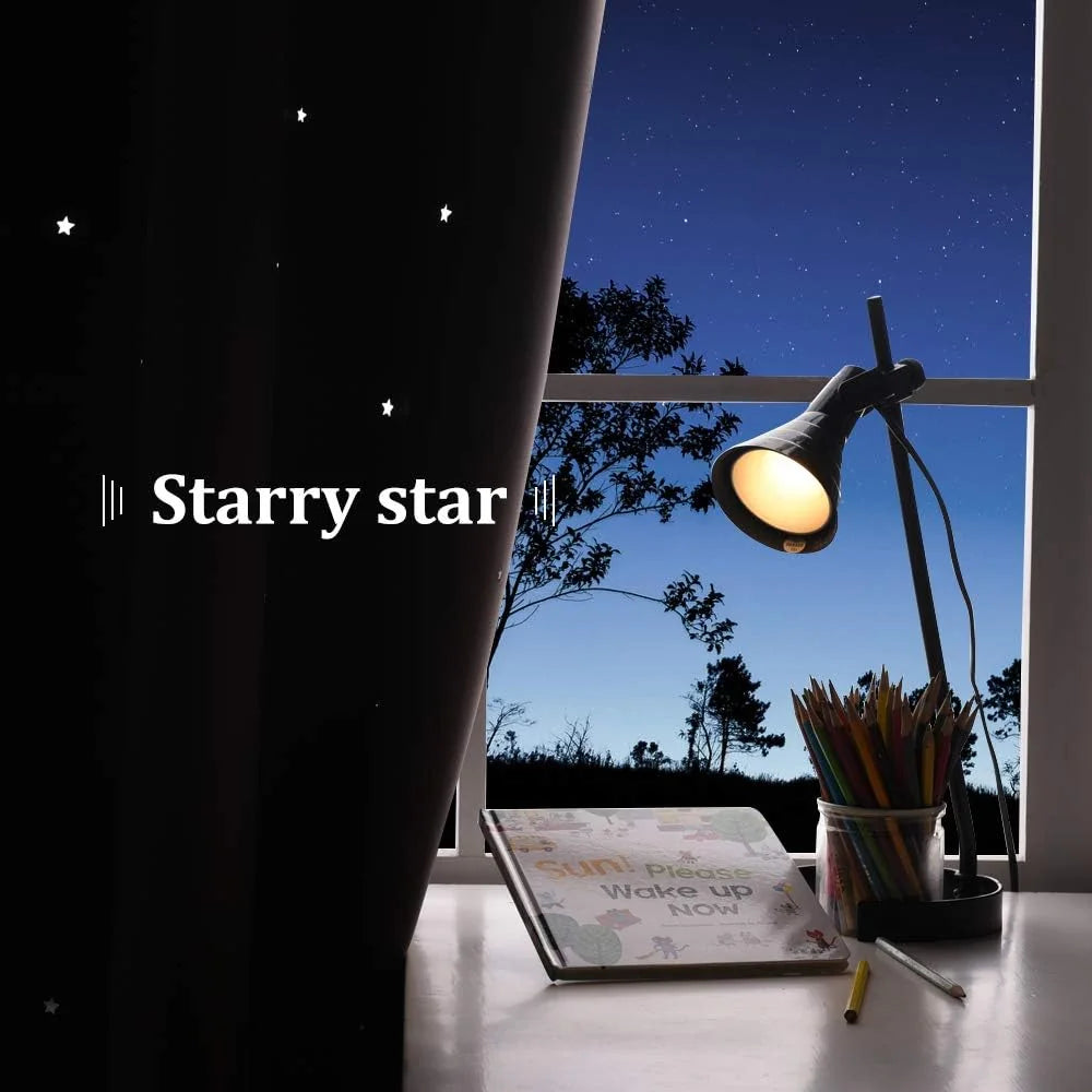 Black starry blackout curtain beside a desk lamp and pencils by a night window