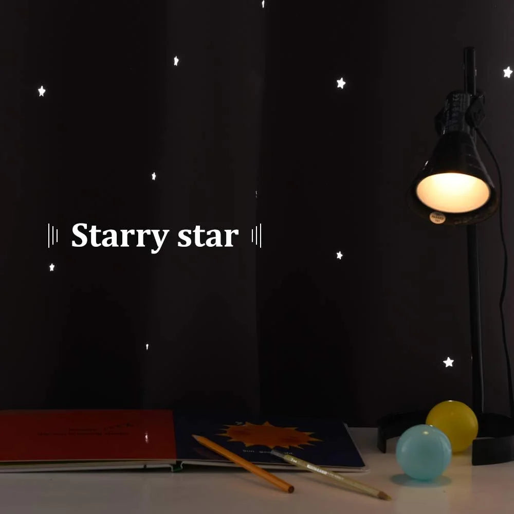 Black curtain with white star pattern beside a lit desk lamp on a kids study table