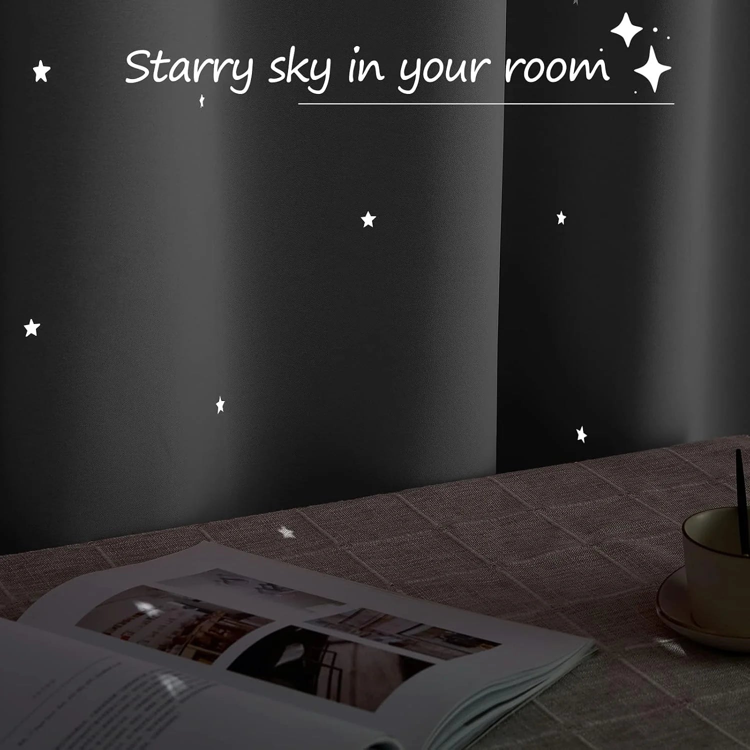Black curtain with glowing star cutouts beside a table with book and cup