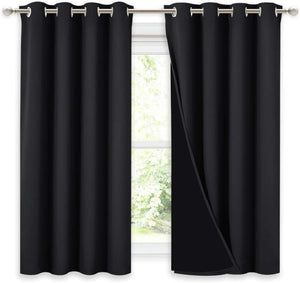 Pair of solid black thermal blackout curtains with silver grommet tops on a curtain rod.