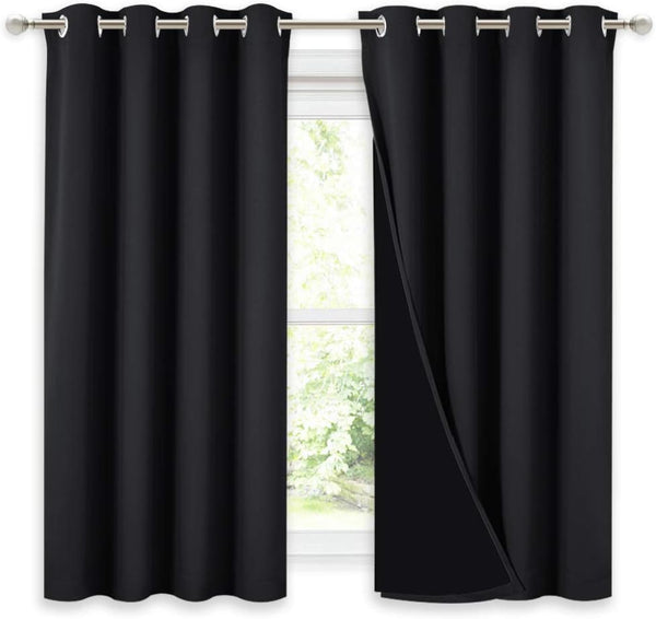 Pair of solid black thermal blackout curtains with silver grommet tops on a curtain rod.