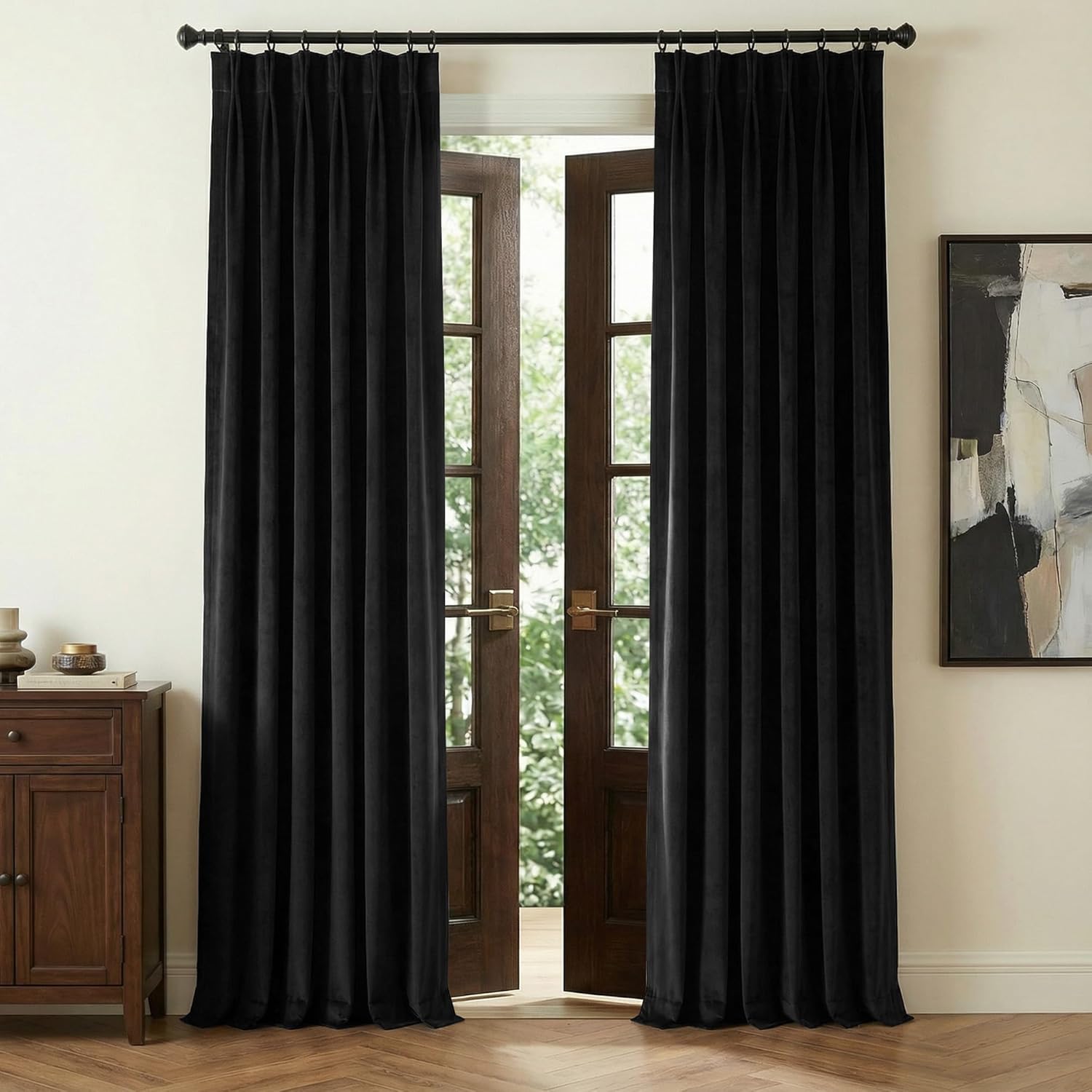 Black velvet pinch pleat curtains hanging on a dark rod, framing open wooden french doors.