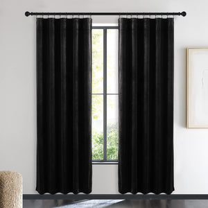 Pair of black velvet pleated blackout curtains hanging from rings on a black rod in a modern living room.