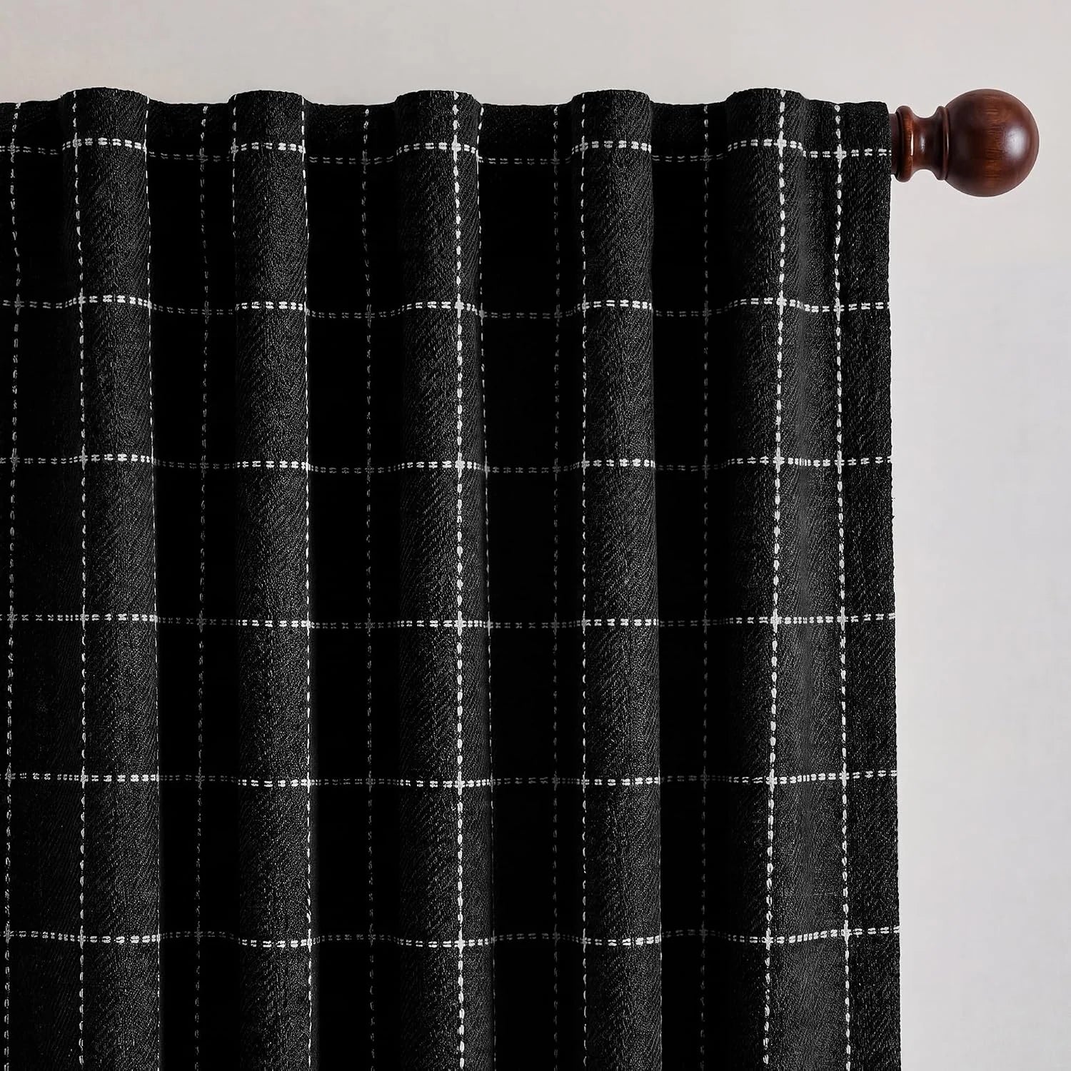 Textured black and white grid plaid curtain panel hanging from a wooden rod
