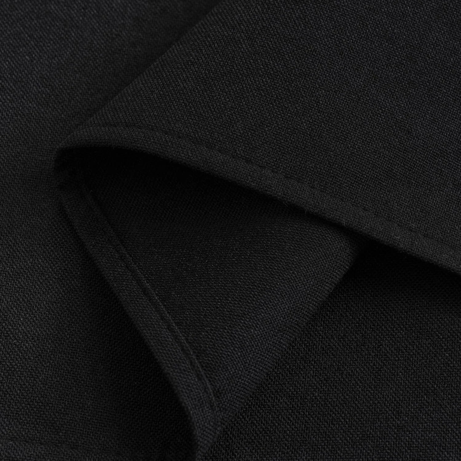 Close-up of black woven fabric, showing fine texture, matte finish, and a subtle fold with a stitched hem.