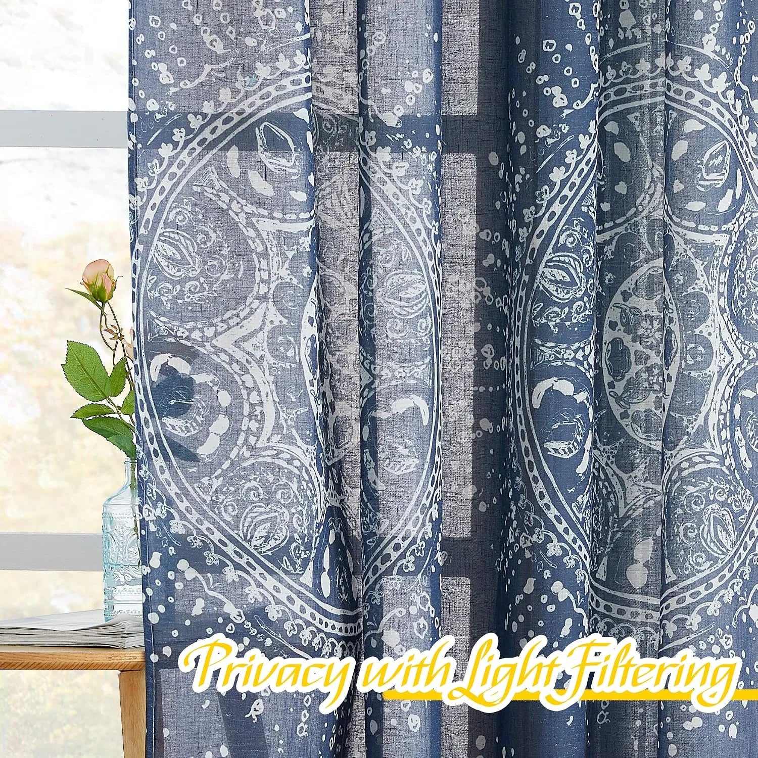 Blue sheer curtains with white boho medallion print filtering light by a window