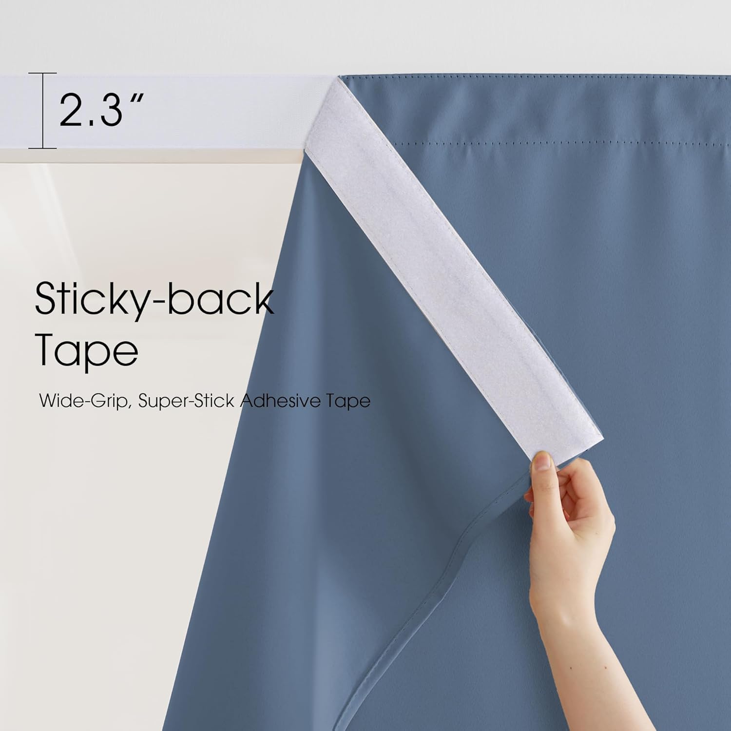 Hand peeling white sticky-back adhesive tape from dusty blue curtain, showing strong wide grip.