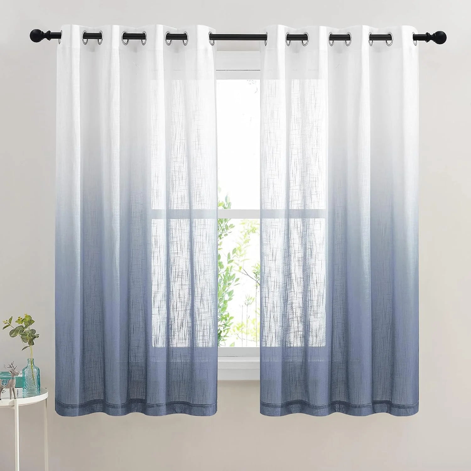 White to blue ombre sheer curtains with silver grommets on a black curtain rod