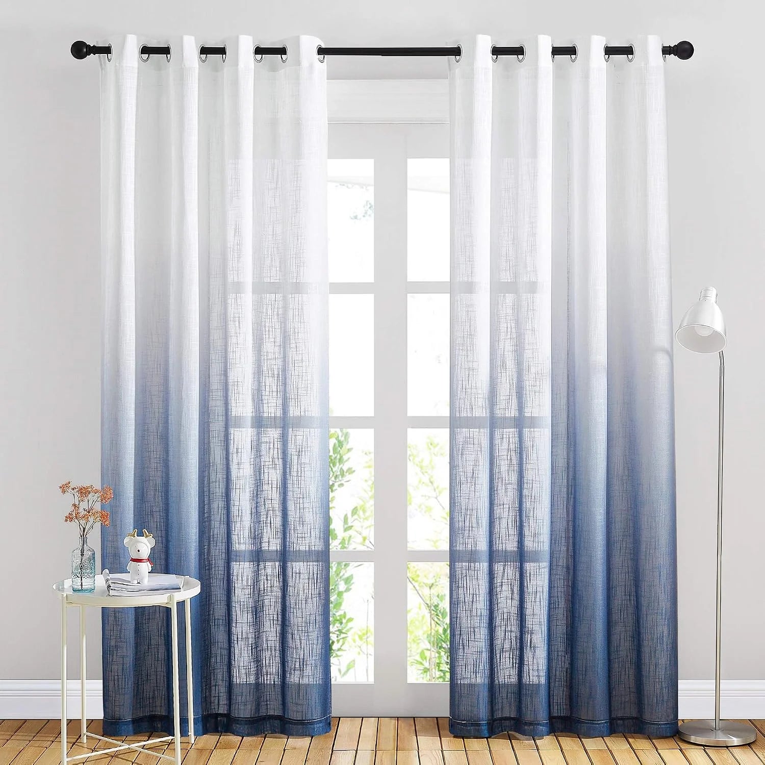 Blue ombre sheer linen curtains with grommet top hanging over a bright window