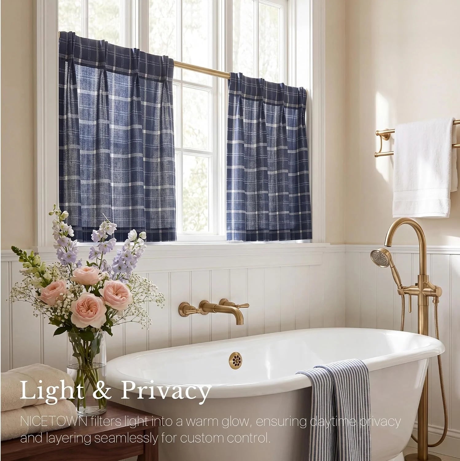 Blue plaid cafe curtains over a bright bathroom window above a white clawfoot tub