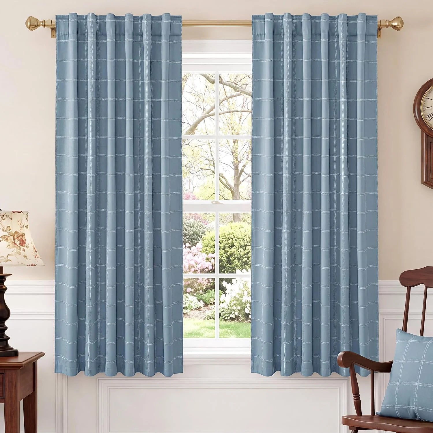 Light blue plaid rod pocket curtains hanging on a brass rod in a bright room