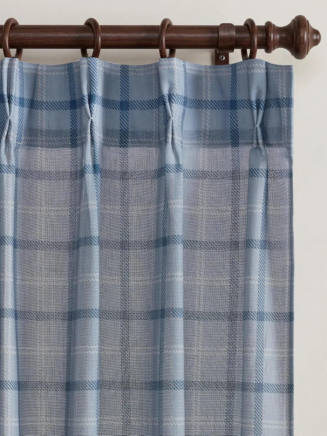 Light blue plaid sheer curtain panel hanging on a dark wooden rod with rings