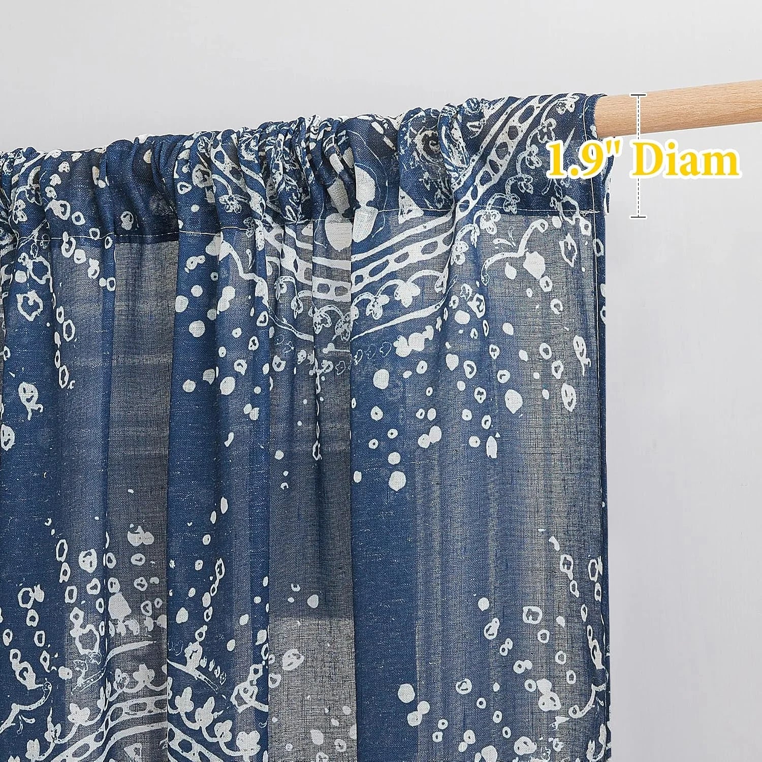 Blue sheer floral rod pocket curtain panel on a light wood curtain rod