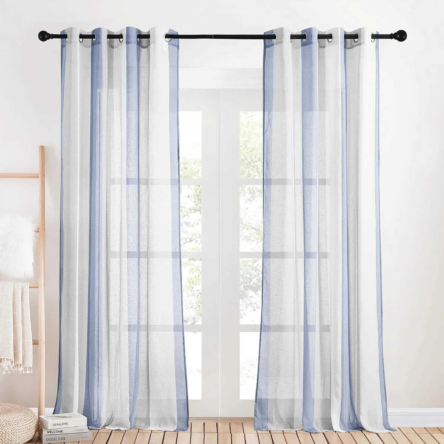 Light blue sheer grommet curtains hanging on a black rod over a bright window