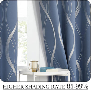 Blue blackout curtains with silver wavy abstract patterns hanging by a sunlit window. A small white table with decor is visible.