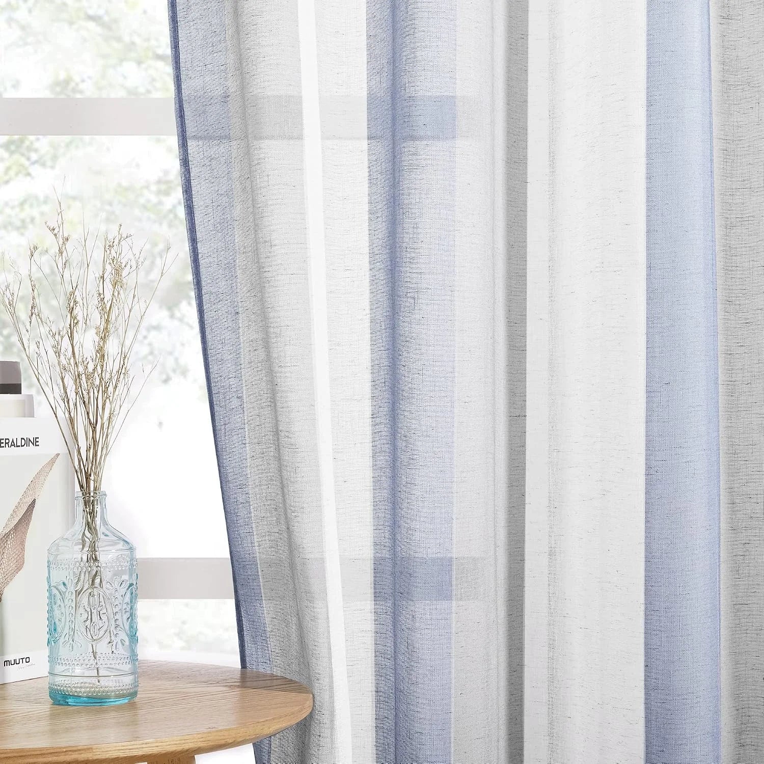 Blue and white striped sheer linen curtain hanging by a bright window