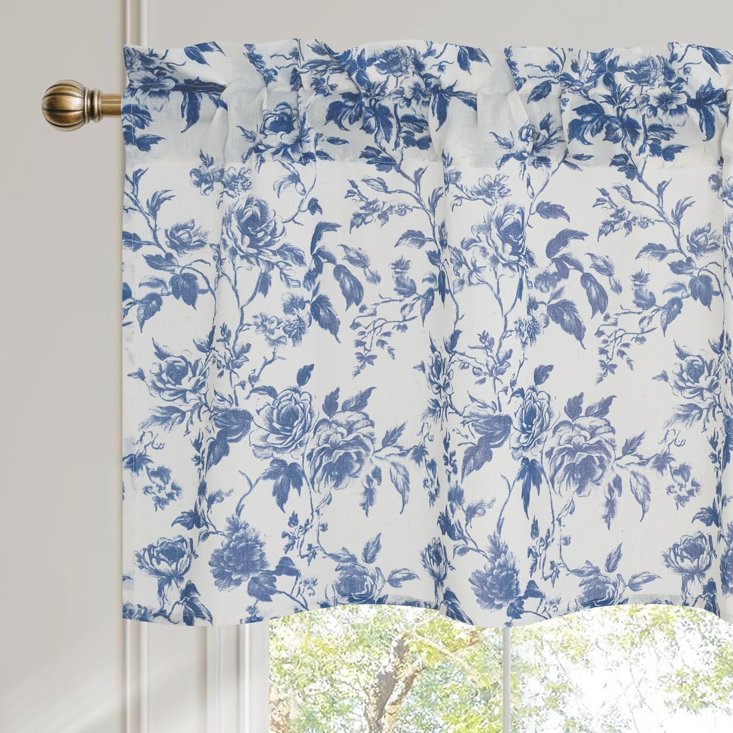Blue and white floral rose valance with rod pocket and scalloped bottom, hanging on a bronze rod.