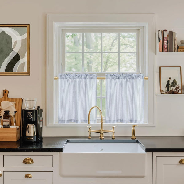 Blue and white striped kitchen tier curtains with gathered top on a gold rod over a window.