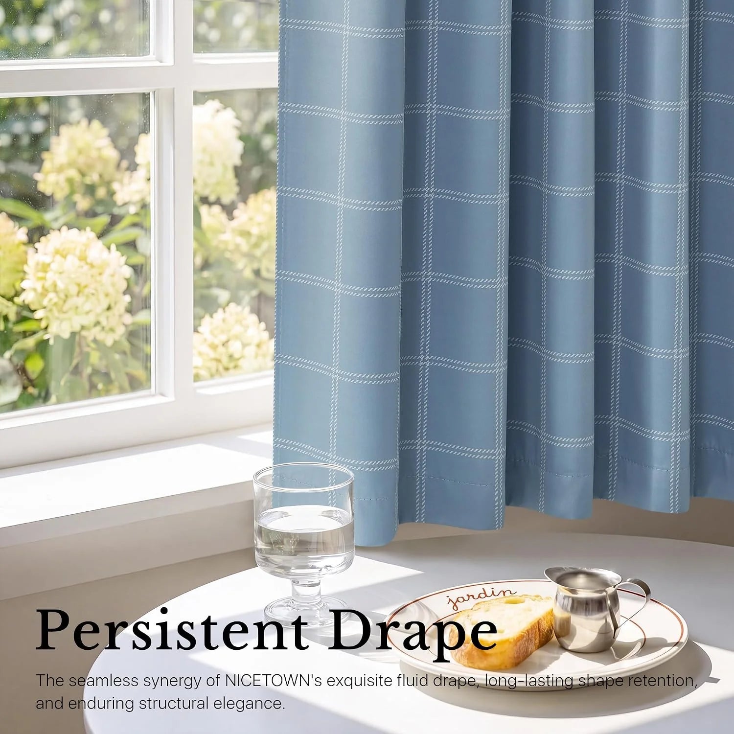 Blue windowpane check cafe curtain draping beside a sunny white kitchen window