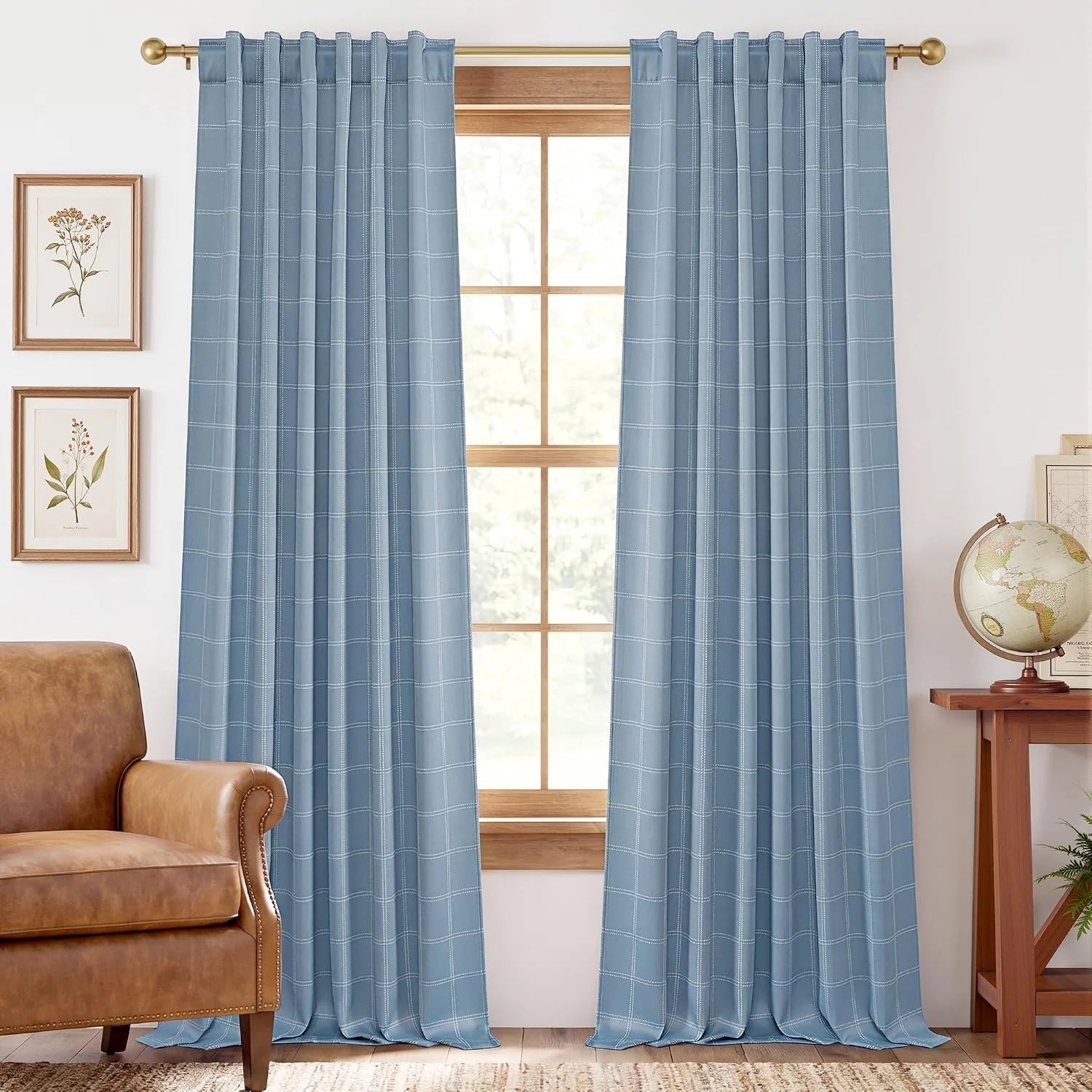 Light blue windowpane plaid curtains hanging on a brass rod in a cozy living room