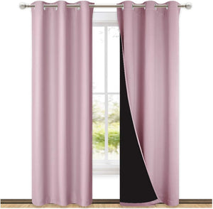 Blush pink blackout curtains with silver grommets on a rod. The visible dark lining confirms room darkening.