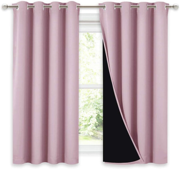 Blush pink blackout curtains with silver grommet tops hanging on a rod. The right panel shows the dark black lining.