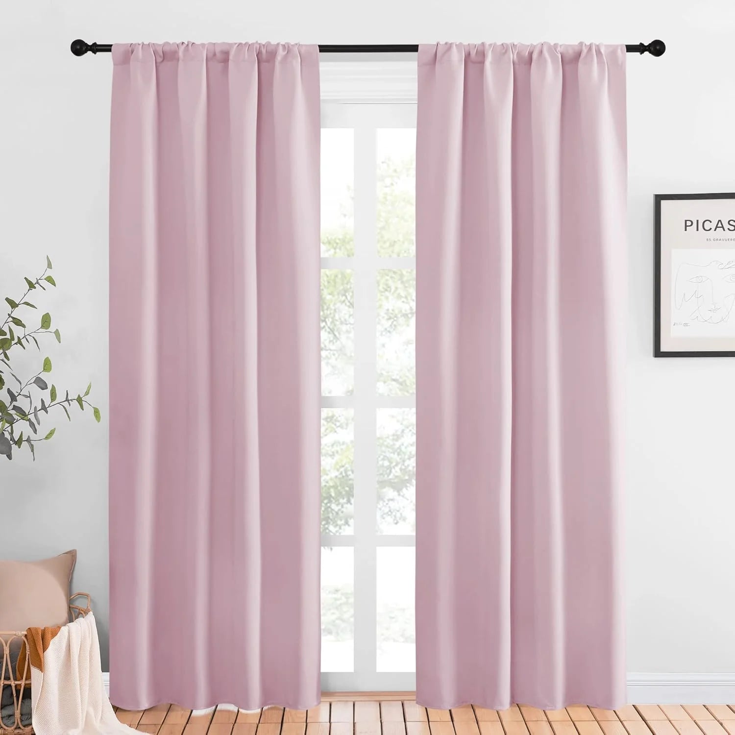 Blush pink blackout curtains hanging on a black rod in a bright modern room