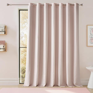 Blush pink grommet top blackout curtain panel hanging on a silver rod covering a window.