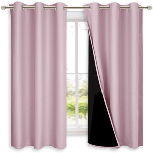 Blush pink grommet top blackout curtains hanging on a silver rod. One panel reveals its black lining.