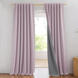 Blush pink linen blackout curtains with dark grey lining, hung on a wooden rod over an arched window.