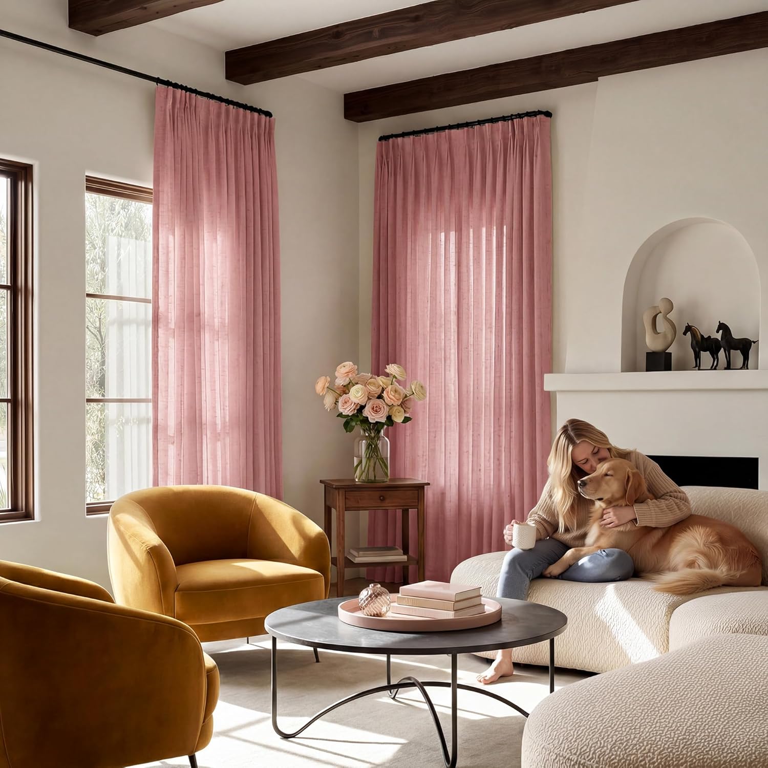 Blush pink linen blend pinch pleat curtains hanging on a black rod, filtering light in a cozy living room.