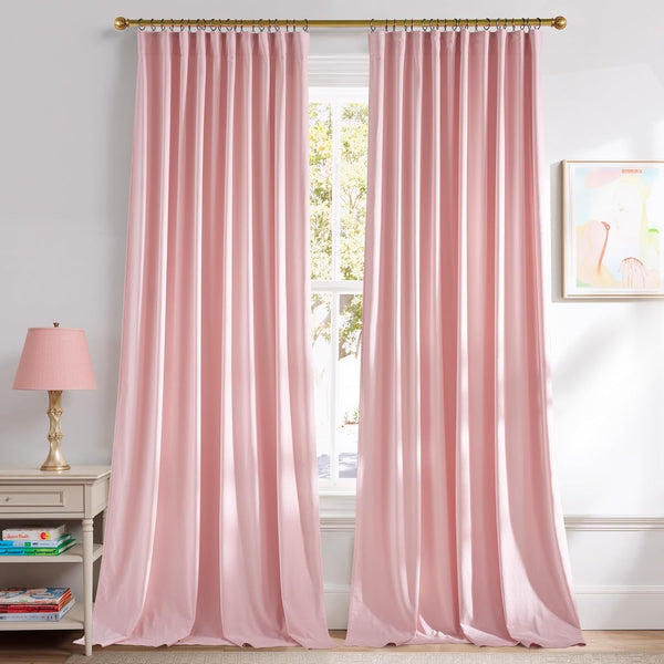 Blush pink pleated curtains on a brass rod covering a bright window, next to a bedside table.