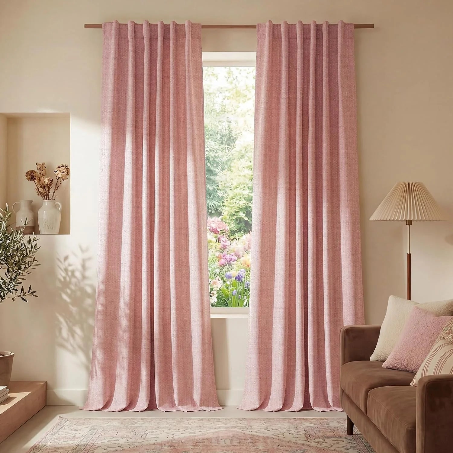 Blush pink textured pleated curtains on a wooden rod in a cozy living room with a brown sofa