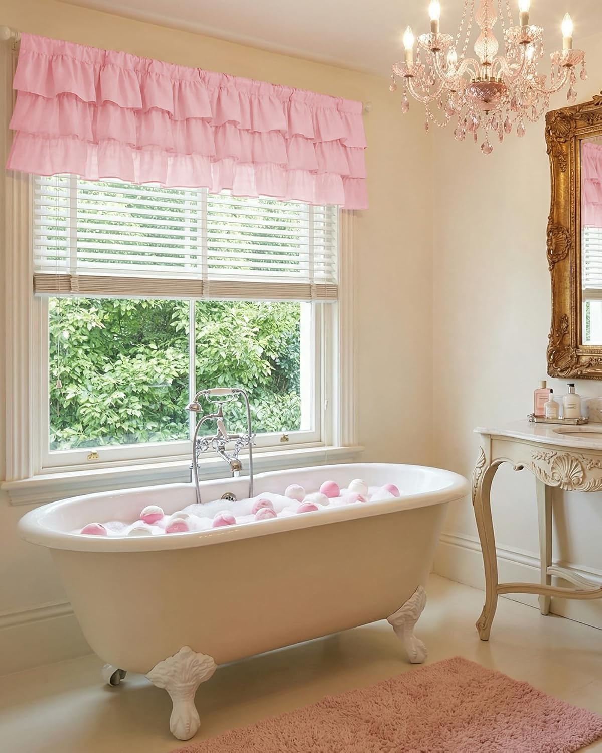 Blush pink tiered ruffle valance hanging over a bathroom window with white horizontal blinds.