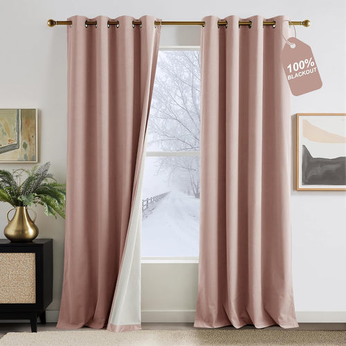 Blush pink velvet 100% blackout grommet curtains hanging on a gold rod, open to snowy view.