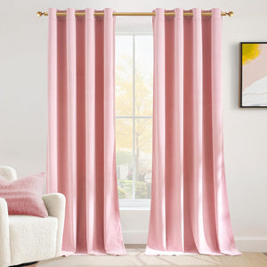 Soft blush pink velvet curtains with gold grommet tops hang on a gold rod by a bright window.