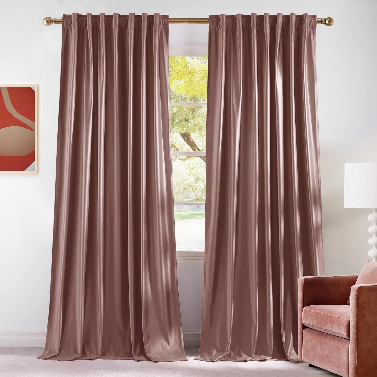 Blush pink velvet rod pocket curtains hanging on a brass rod in a bright living room