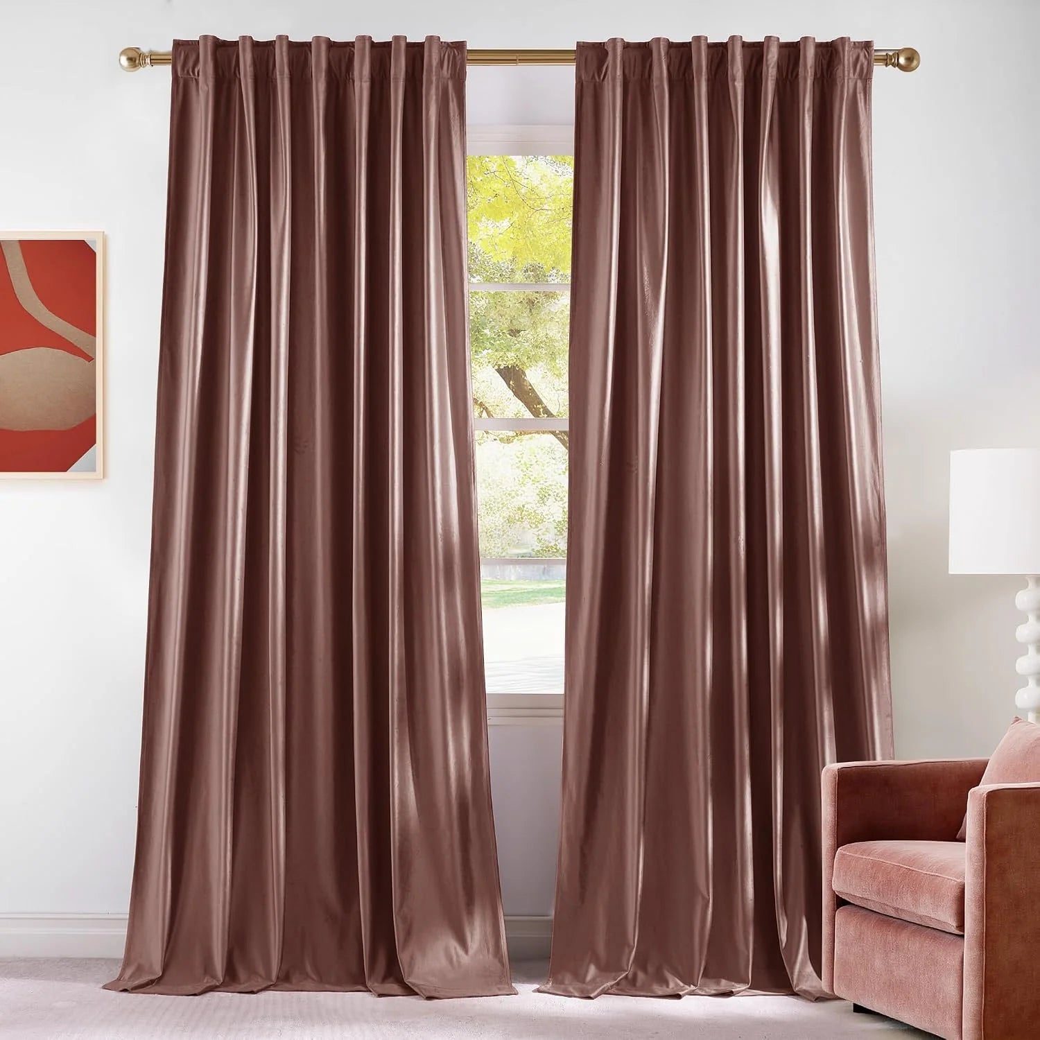 Blush velvet rod pocket curtains hanging on a gold rod in a bright modern room