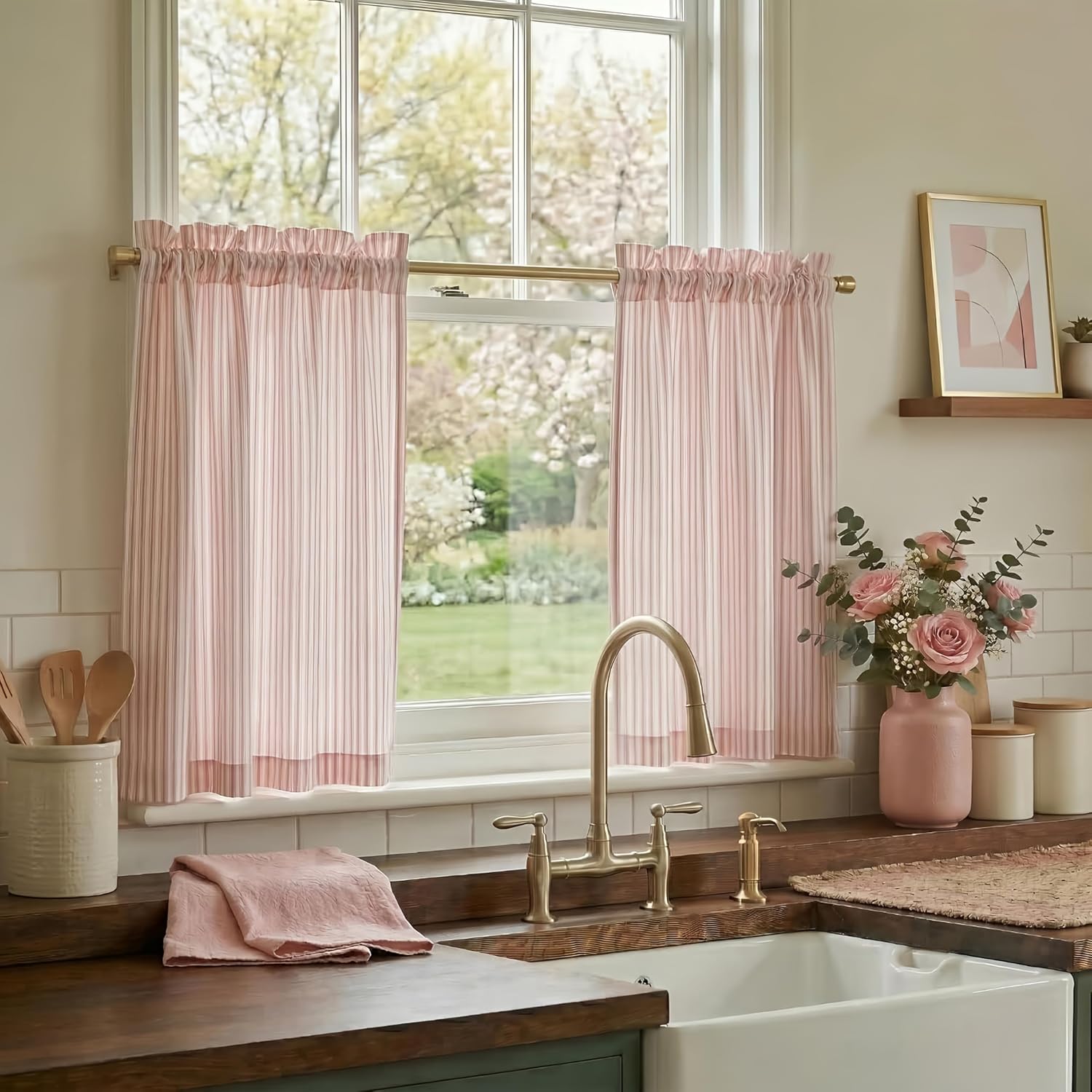 Blush and white striped ruffled tier curtains on a brass rod in a bright kitchen window.