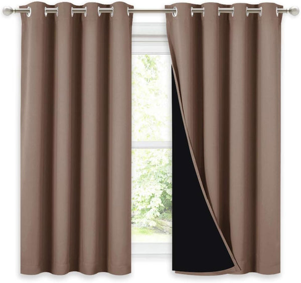 Pair of brown blackout curtains with silver grommets on a rod, one revealing its dark lining.