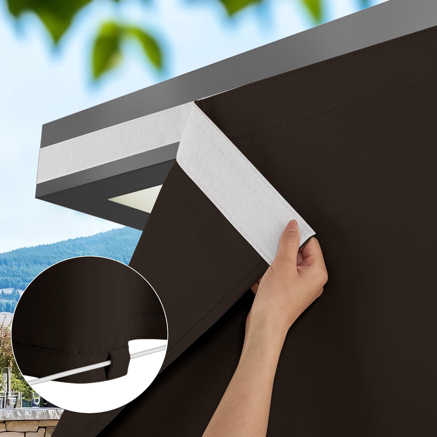 Hand attaching brown outdoor pergola shade with Velcro to a grey beam. Bottom loop visible with white cord.