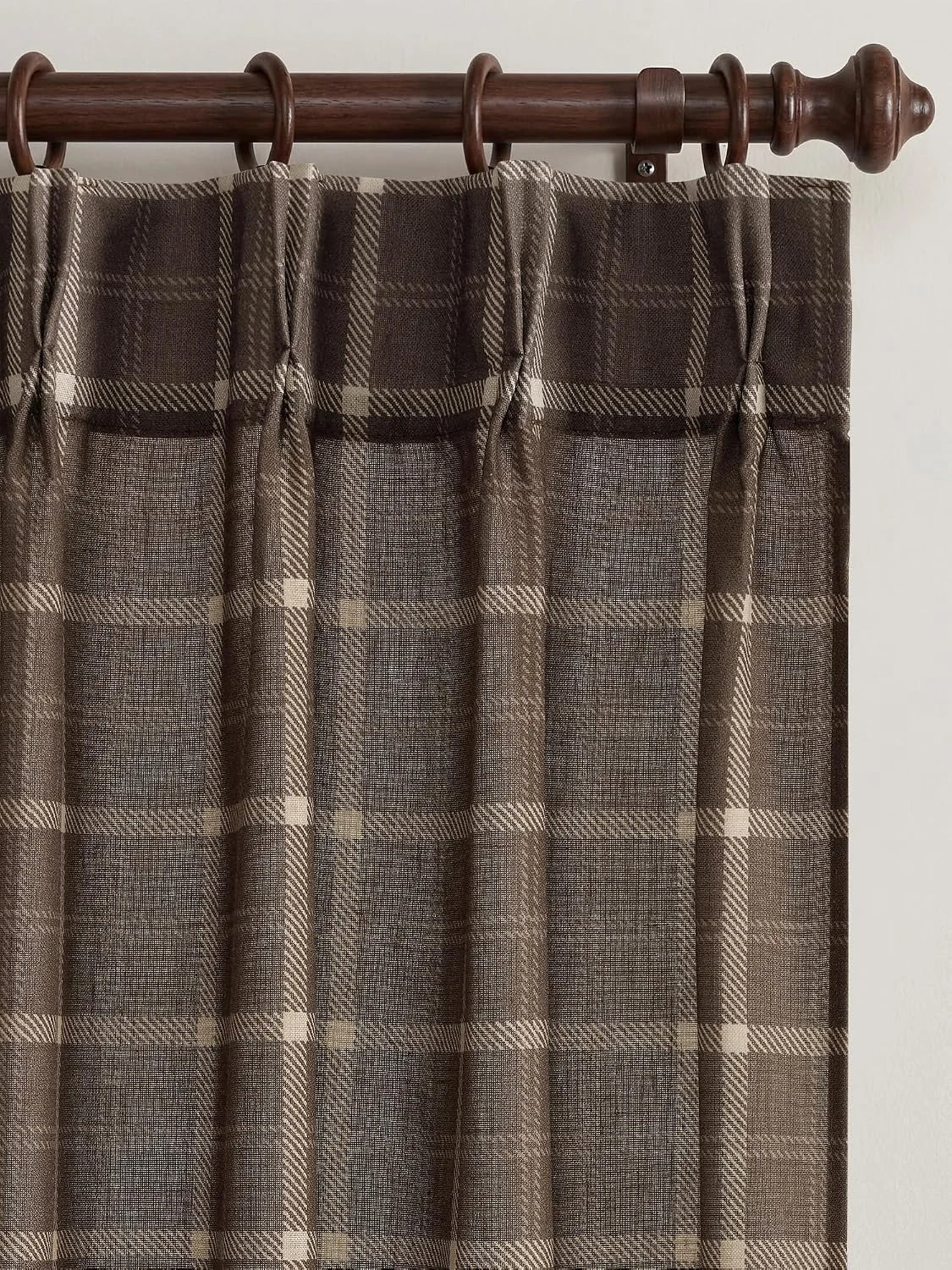 Brown plaid tab top curtain hanging from a dark wooden rod in close-up