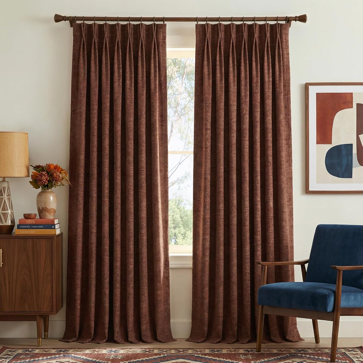 Rich brown textured fabric pinch pleat drapes covering a window in a bright room.
