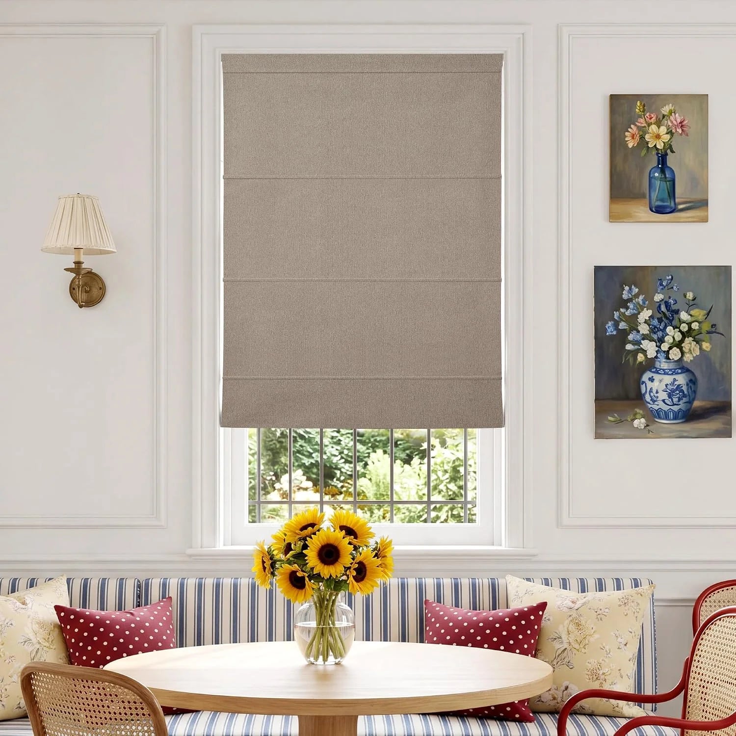 Light brown textured Roman shade installed in a dining nook with a striped banquette, wooden table, and sunflowers.
